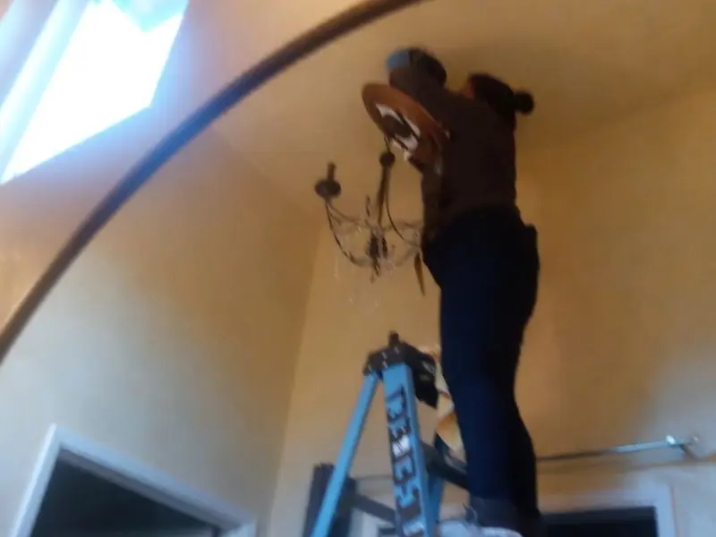 Electrician installing a chandelier in a Brooklyn Park residence